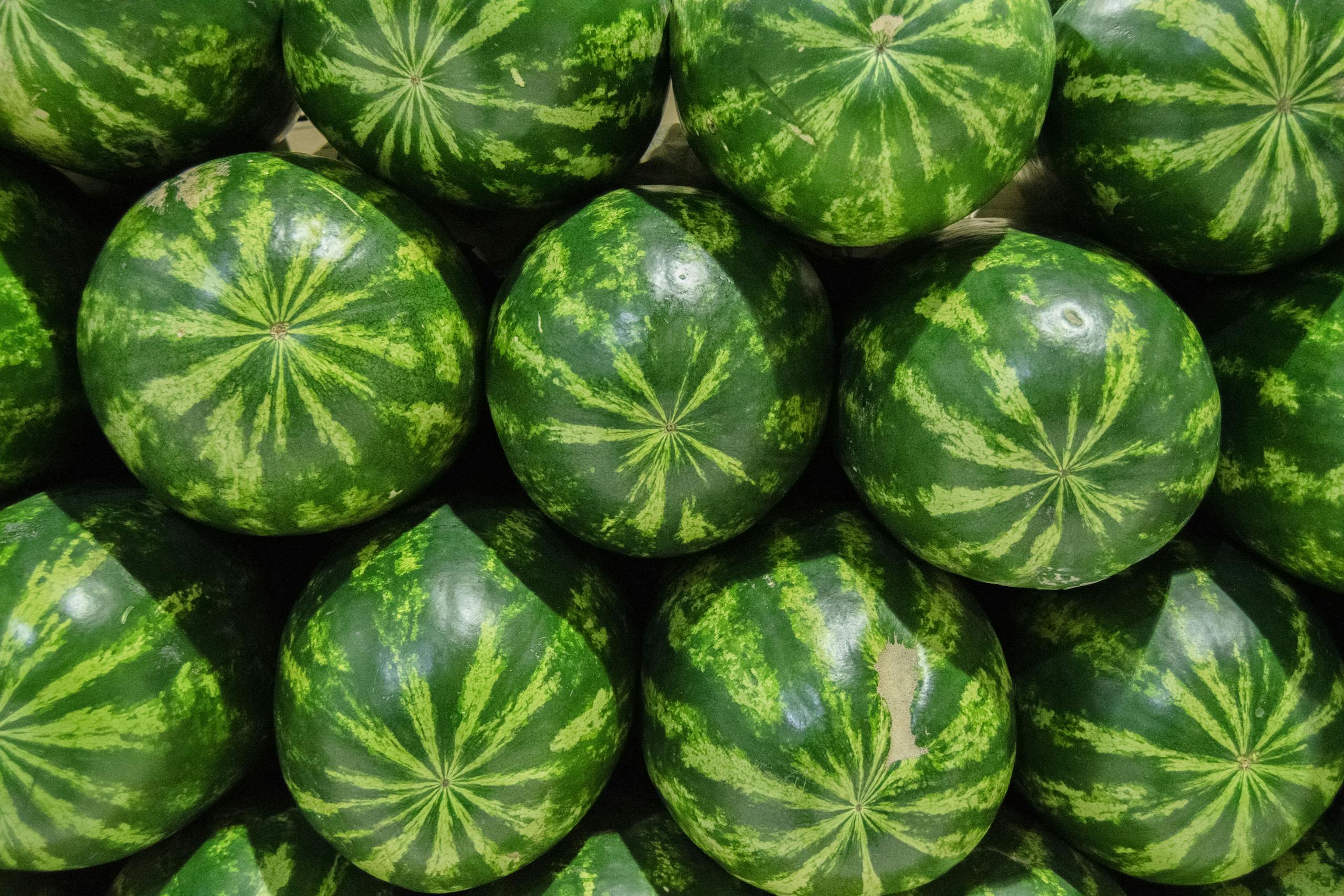 Close-up of fresh green watermelons stacked in vibrant arrangement, perfect for summer themes.